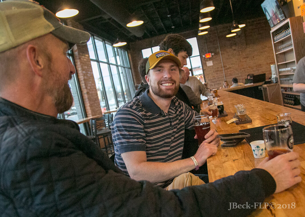 Men sitting at a bar drink craft beer